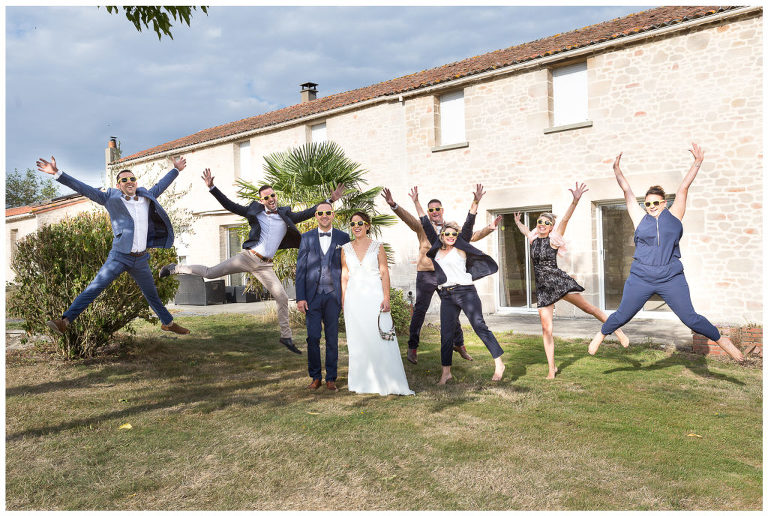 Les amis proches des mariés sautent autours de leurs amis pour une photo de groupe fun et décalée.